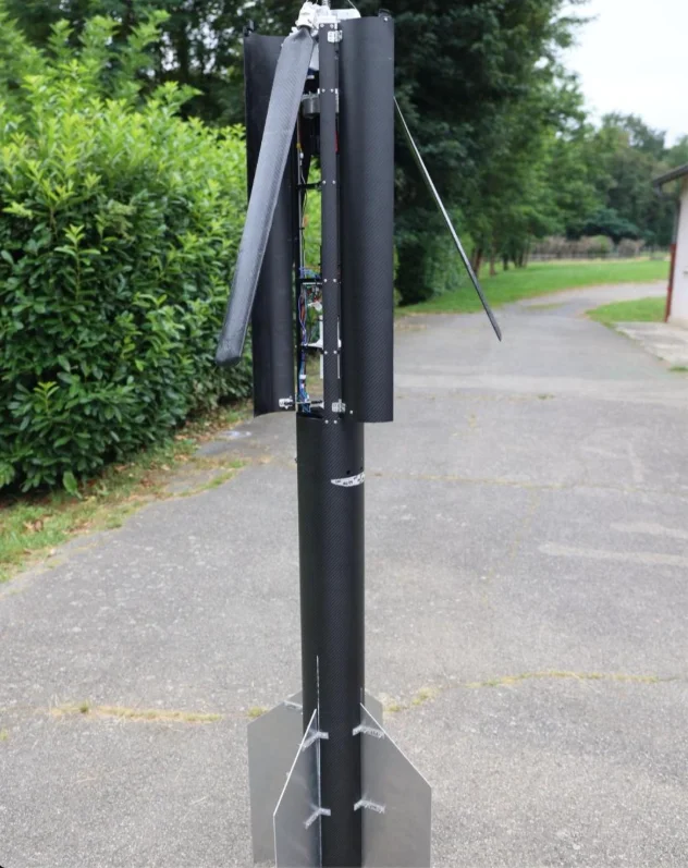 The finished black rocket standing outdoors with its three blades half deployed